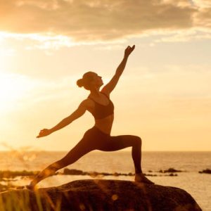 caucasian fitness woman practicing yoga at sunset